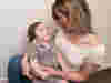A woman with blonde hair looking and holding her child, smiling at him