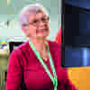 A volunteer looking at a computer smiling at the reception desk at Demelza, Kent