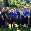 Nine female East Sussex team members stand side by side in a garden on a sunny day, smiling.