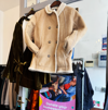 A brown coat with a fur collar hanging up above a rail of different shirts and coats at Rochester's Demelza charity shop