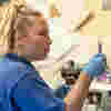 Nurse Ella, wearing a blue uniform, glasses on her head, and gloves on her hands, preparing medication.