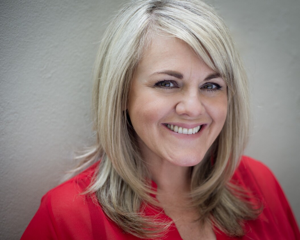 Headshot of Sally Lindsay, Demelza celebrity ambassador, smiling in a red top with blonde hair.