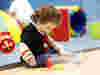 A child in the soft play area looking down at bowling pins
