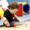 A child in the soft play area looking down at bowling pins