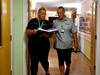 Two nurses, in uniform, walking next to each other whilst in the Kent Care Corridor, discussing information from a folder one of them is holding.
