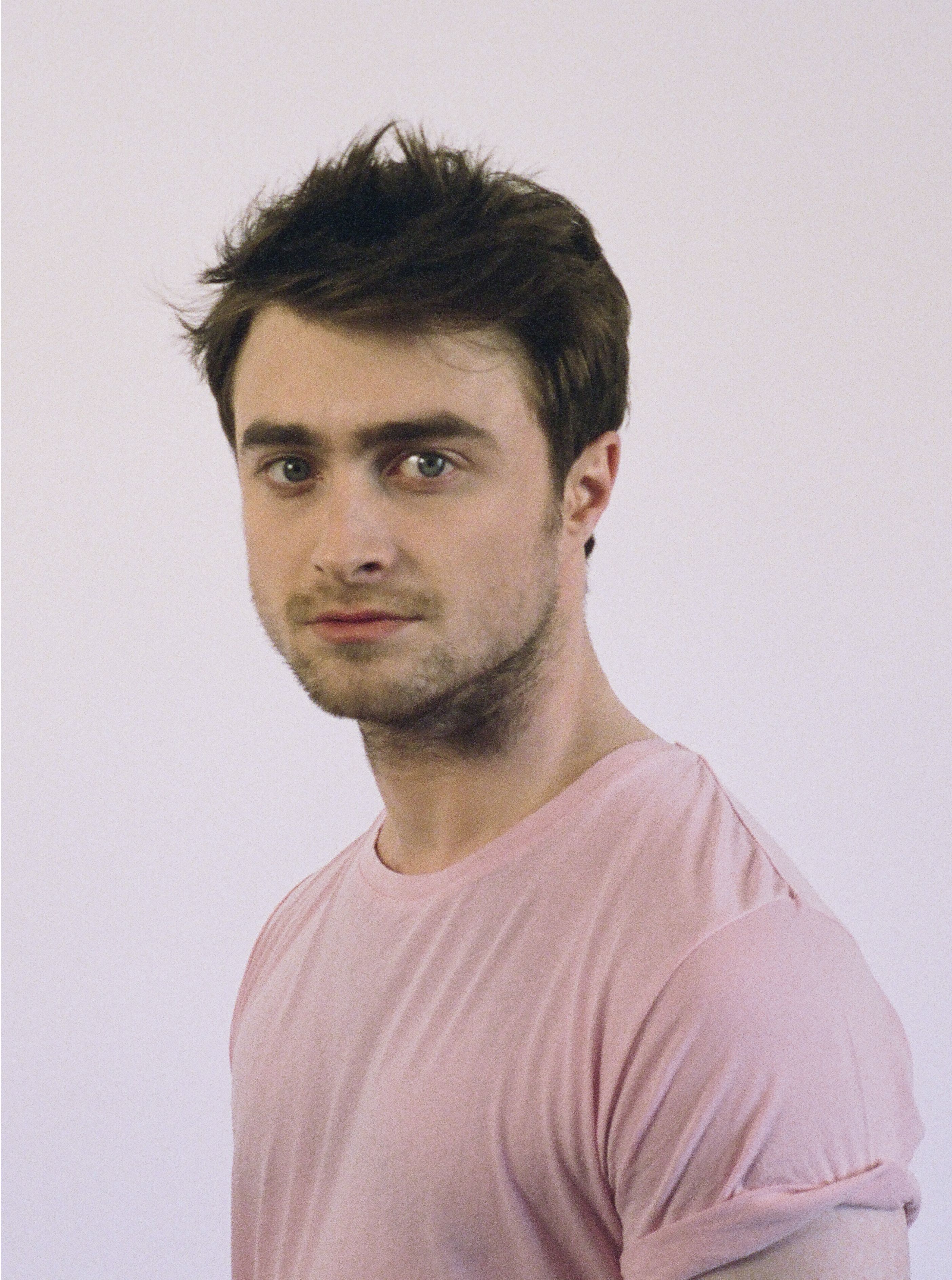 Headshot of a young Daniel Radcliffe, Demelza celebrity ambassador, wearing a pink t-shirt with a neutral expression.