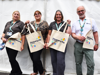 Staff and volunteers hold Demelza tote bags outside a white marquee at Family Discovery Day 2025, smiling and ready to greet guests.