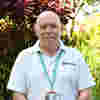 A man with no hair outside in the tranquility garden smiling towards the camera