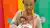 A woman holding her baby daughter looking towards the camera in Demelza's soft play room