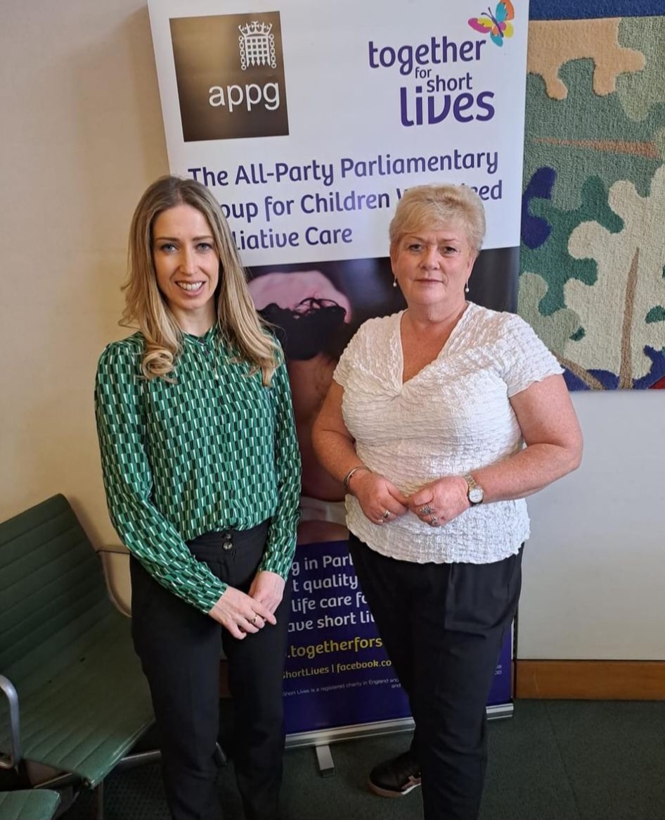Two people stand in front of a banner reading 'The All-Party Parliamentary Group for Children Who Need Palliative Care' with logos for 'APPG' and 'together for short lives'.