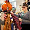 Lady with grey top and hair tied up arranging a clothing display in a charity shop