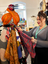 Lady with grey top and hair tied up arranging a clothing display in a charity shop
